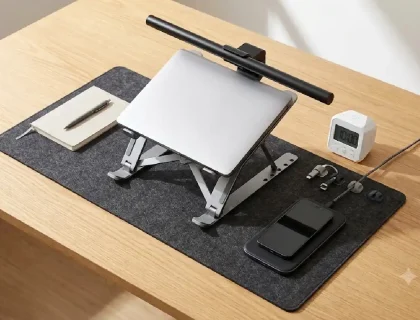 15 affordable office gadgets under $50 arranged on a clean desk including laptop stand, monitor light bar, and cable tray