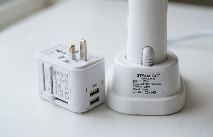 dual voltage travel steamer label next to a plug adapter