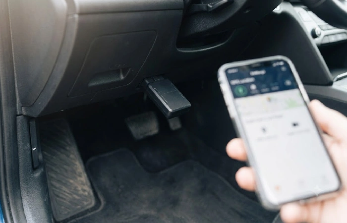 Close-up of OBD-II GPS tracker plugged into car port below steering wheel