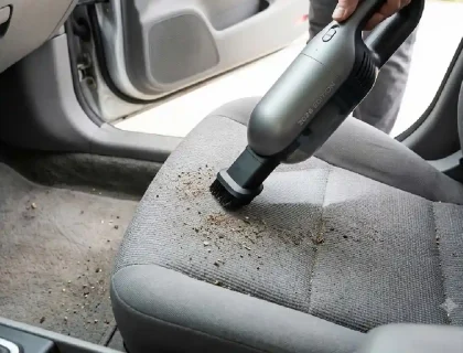 Portable car vacuum cleaner being used to clean a car's interior seat and floor