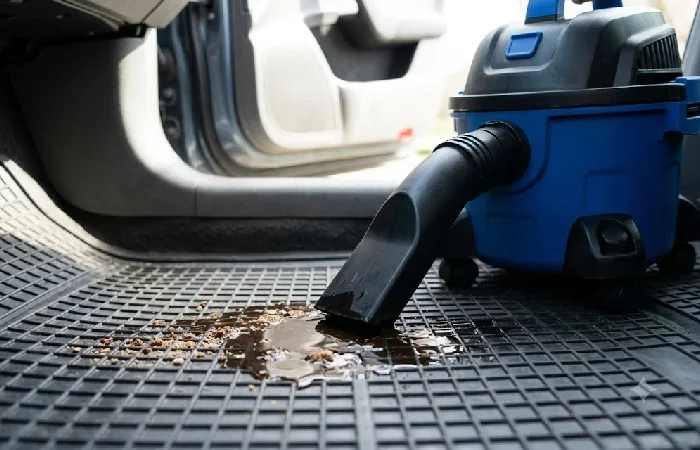 Wet dry car vacuum cleaning a spilled liquid off a floor mat